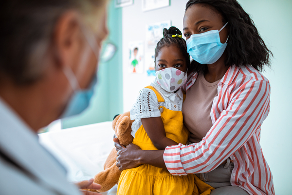 Mother holding daughter in doctor's office