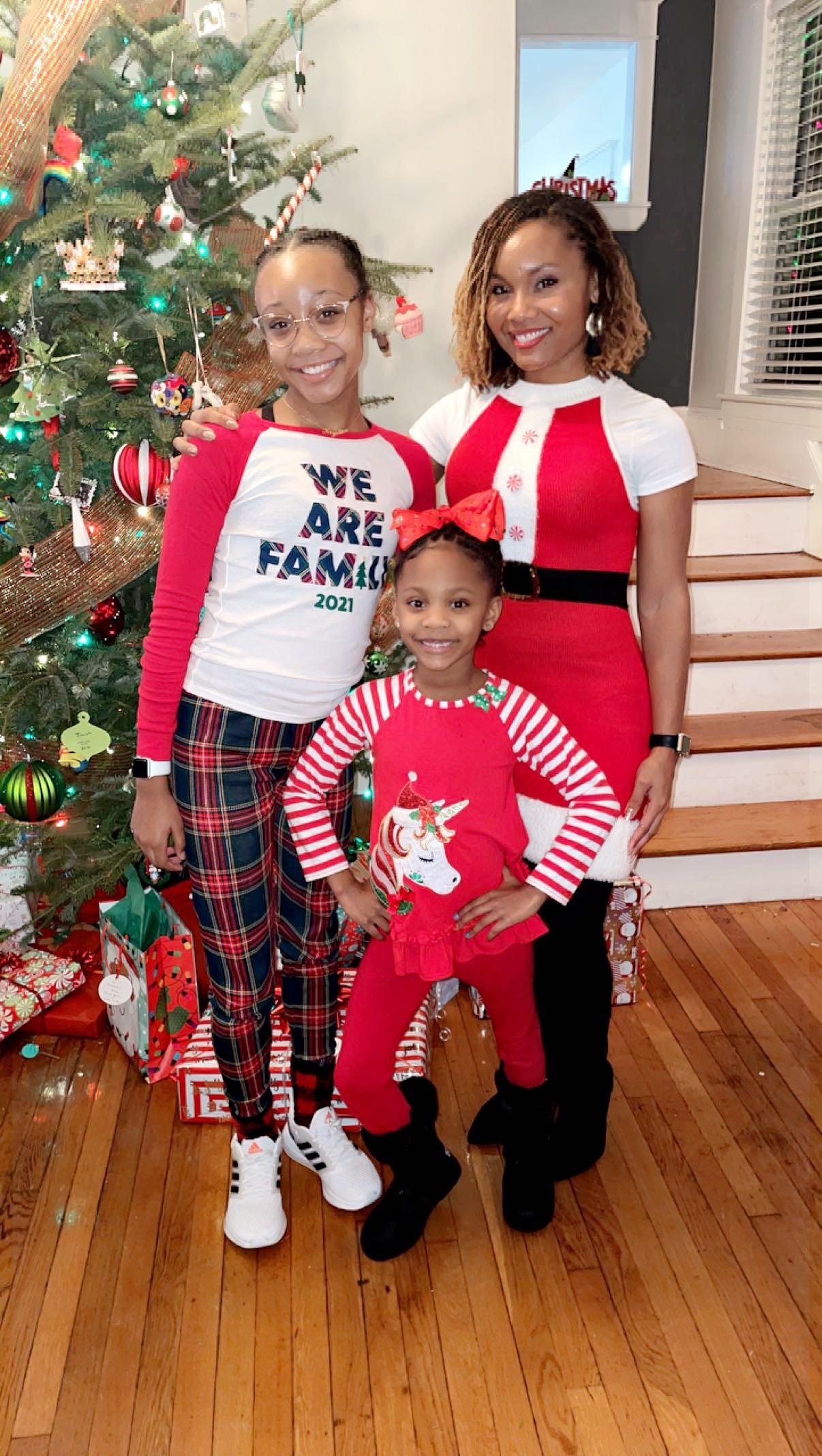 Katrina Elliott poses with her two young daughters with a Christmas tree in the background