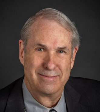 A person in a suit smiling

Description automatically generated