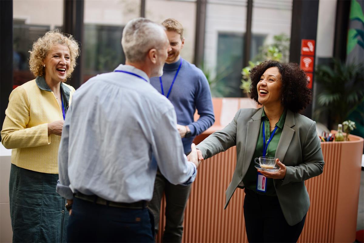 Conference attendees greet one another with a handshake.