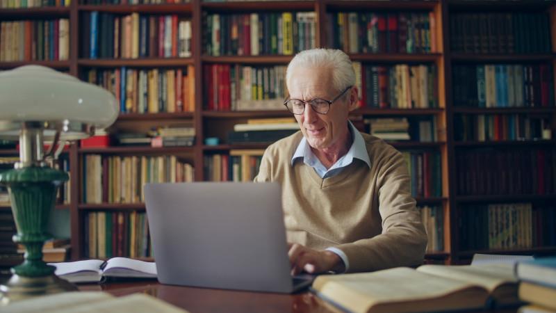 A man works on his laptop in a library.