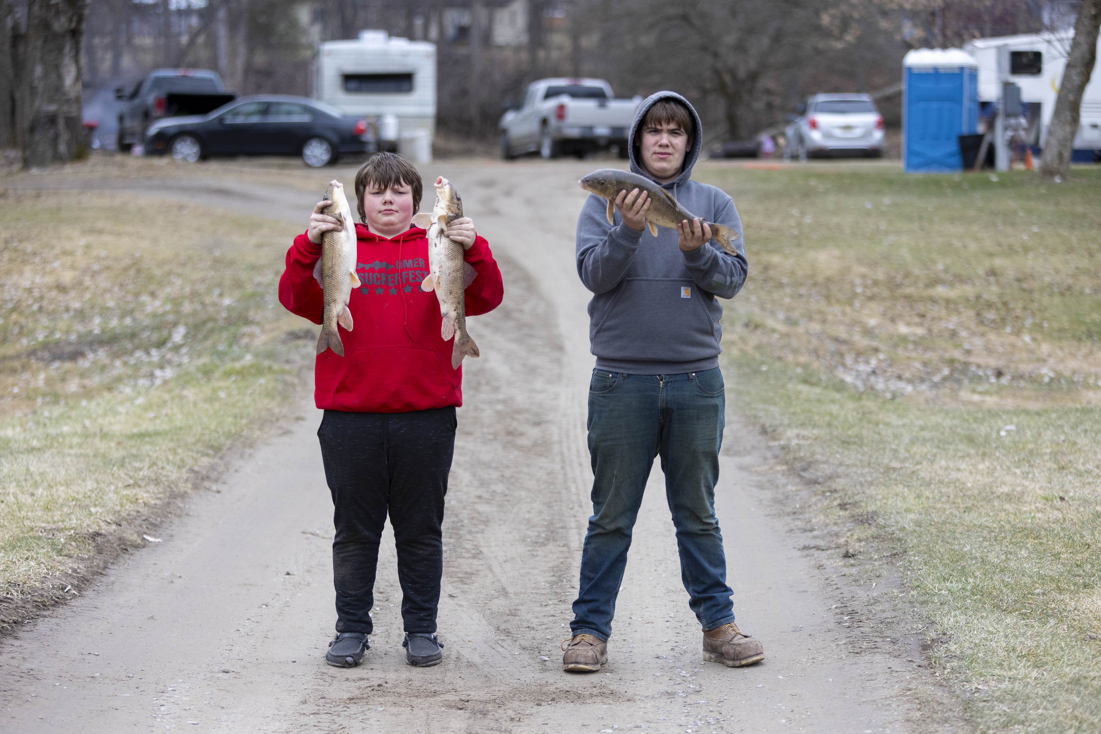 Two 14-year-old boys hold sucker fish they caught.