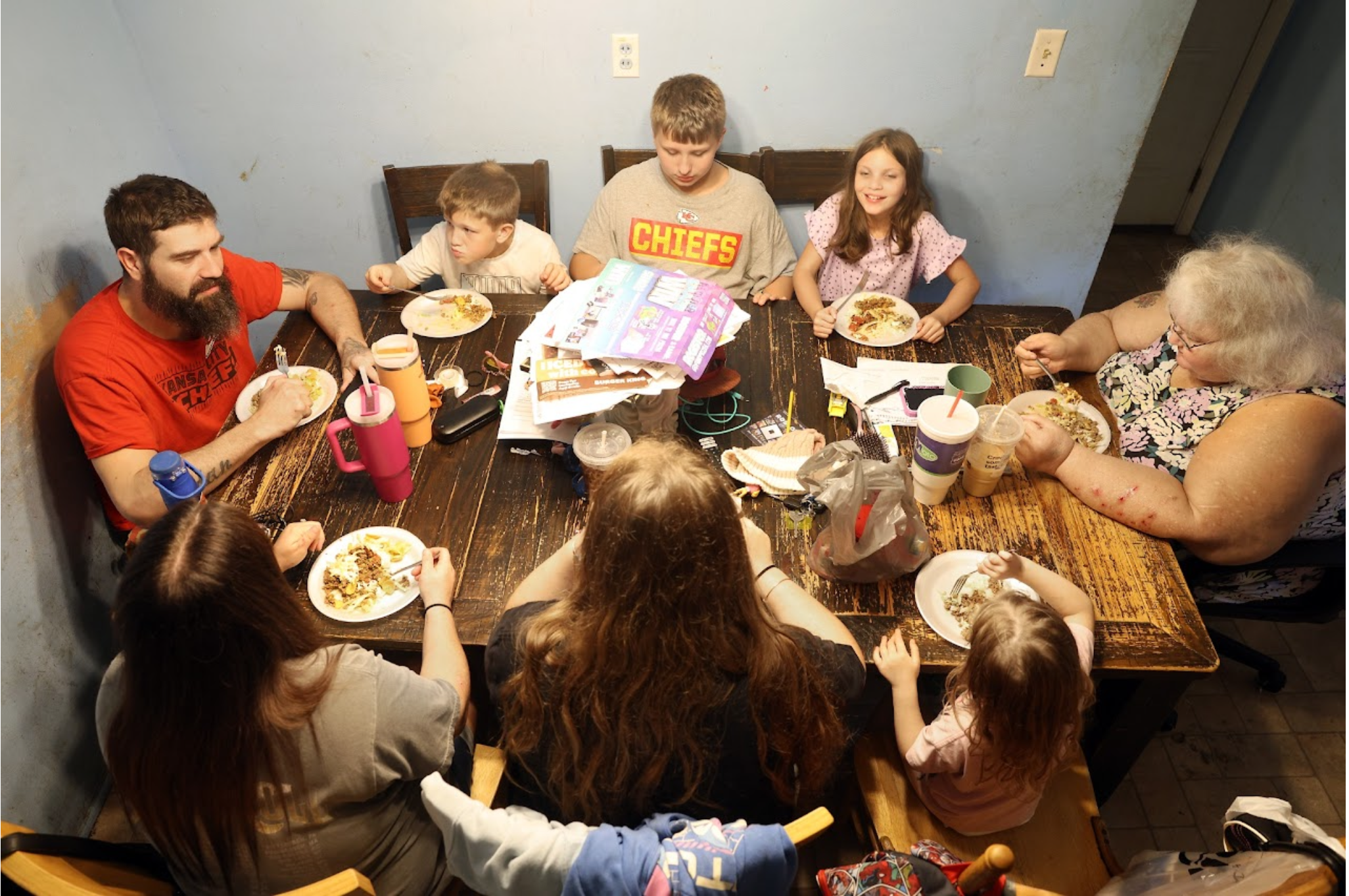 A family of eight having a meal together around a table.