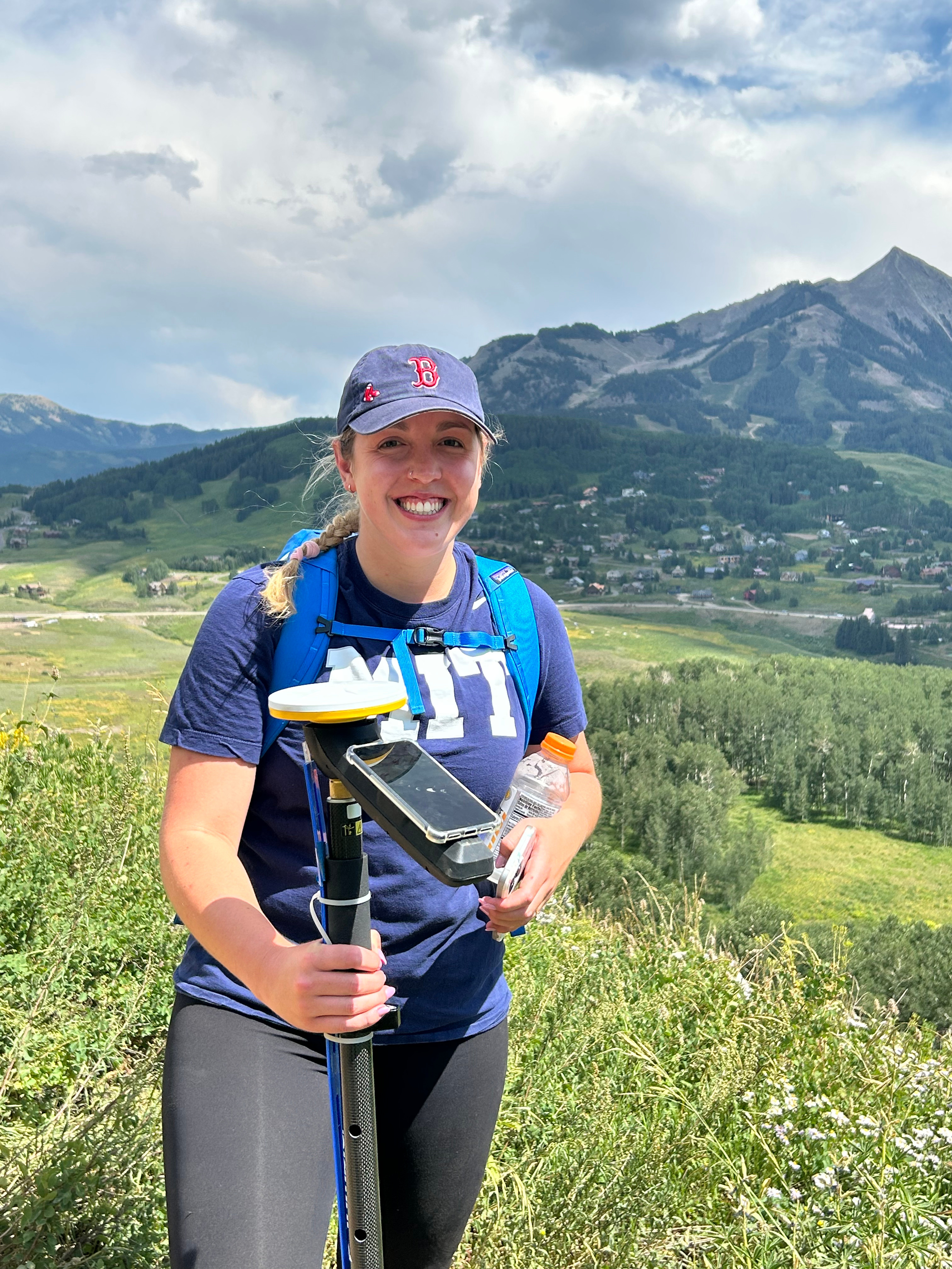 Person standing in scenic valley holding GPS equipment