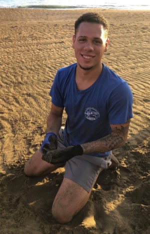 Angel Reyes Delgado holds a baby leatherback sea turtle while monitoring turtle nests for the Chelonia research and conservation organization. (Photo credit: Chelonia staff)