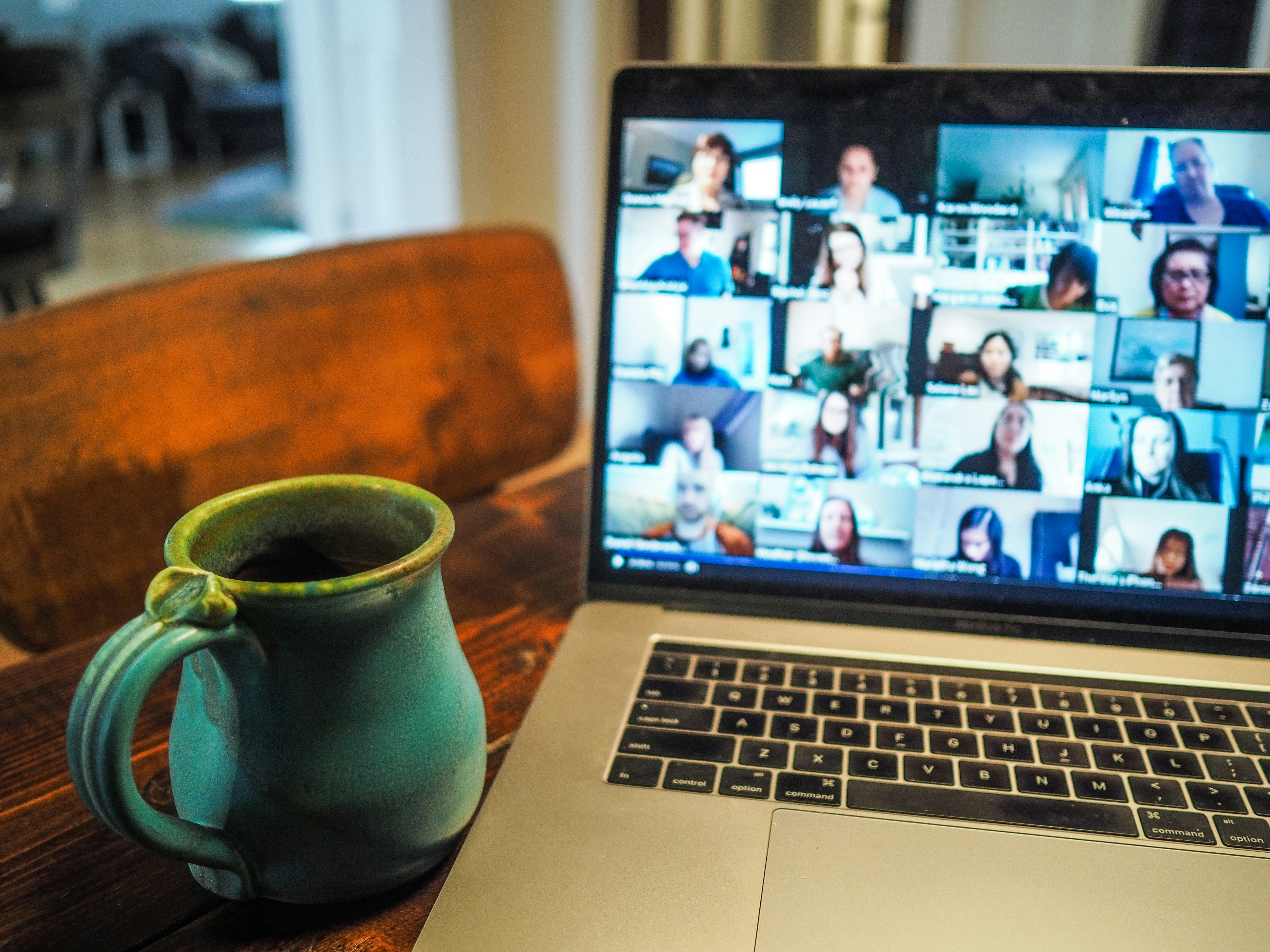 A desk with an open laptop with a cup of coffee beside it.