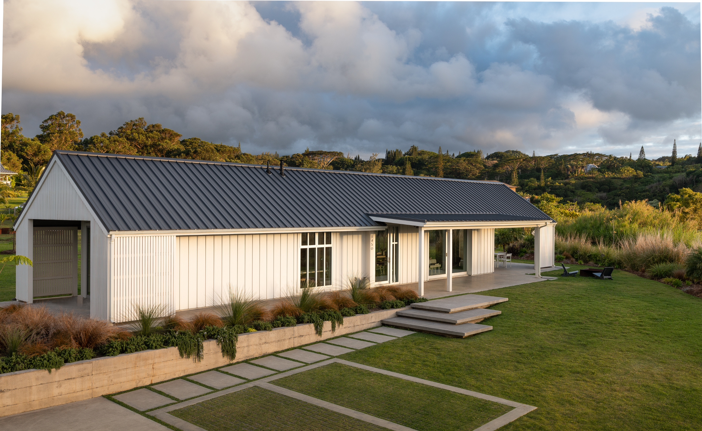 A landscape view of the Haiku Cottage, lit by an early evening sun with clouds filling the sky.