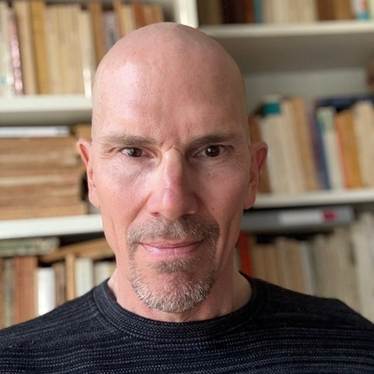 Dr. Marcel O'Gorman, a bald man with a goatee, wearing a black shirt.