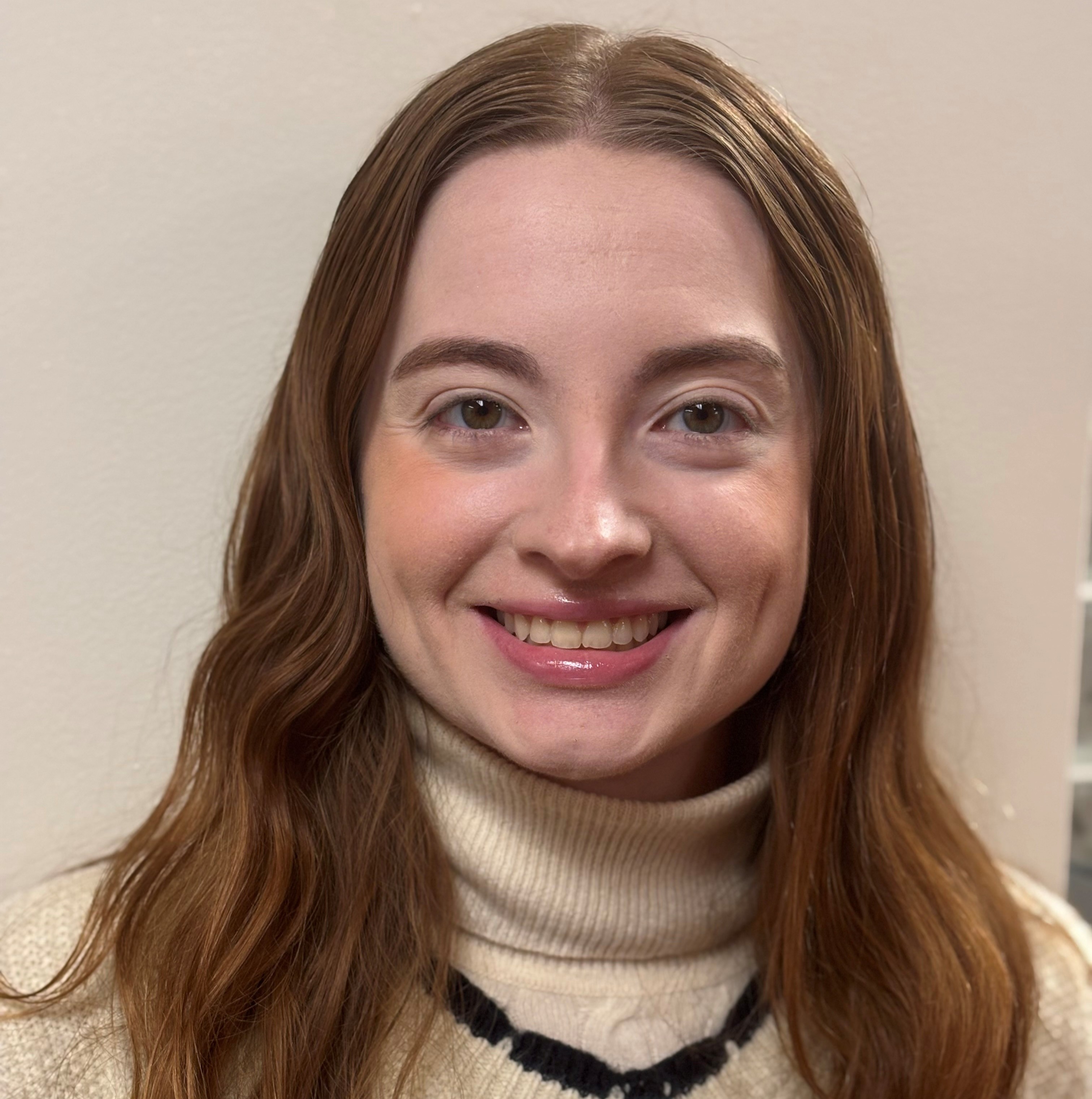 Woman with red hair smiling wearing a white shirt against a white background