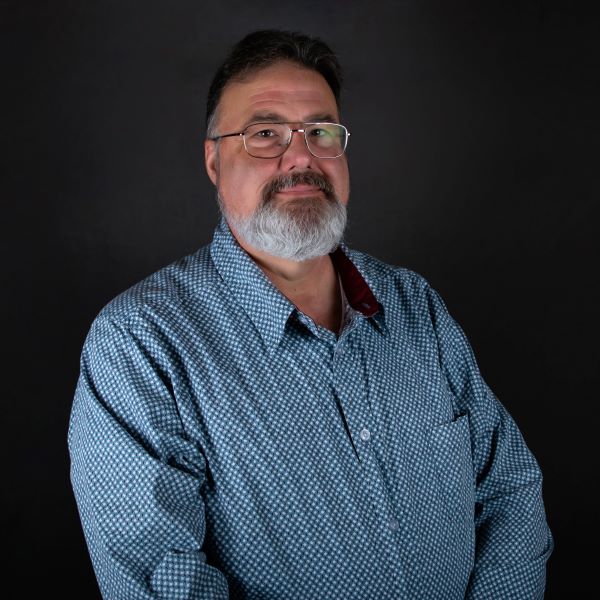a man in a blue shirt smiling with a beard