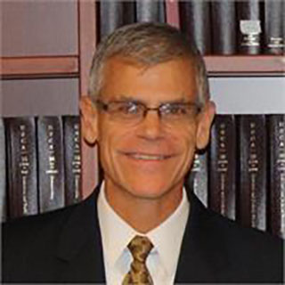 a man with glasses and wearing a suit smiles