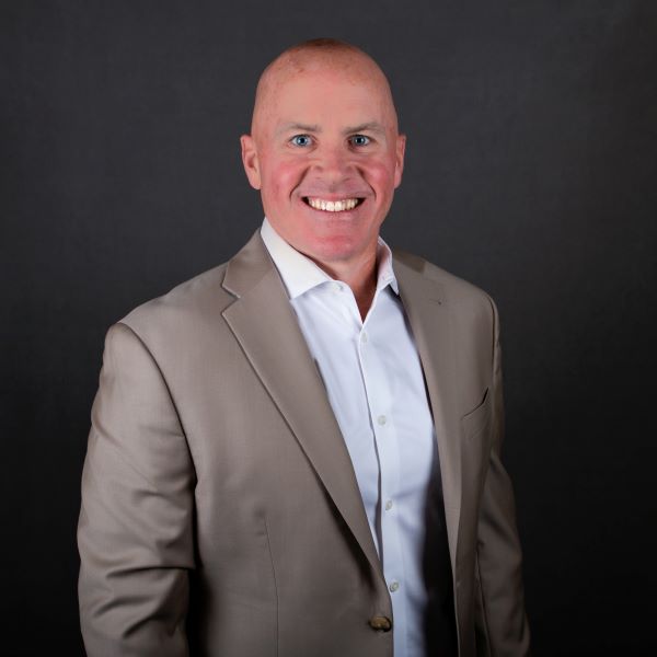 a man with a tan suit smiles