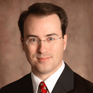 a man with glasses and brown hair smiles