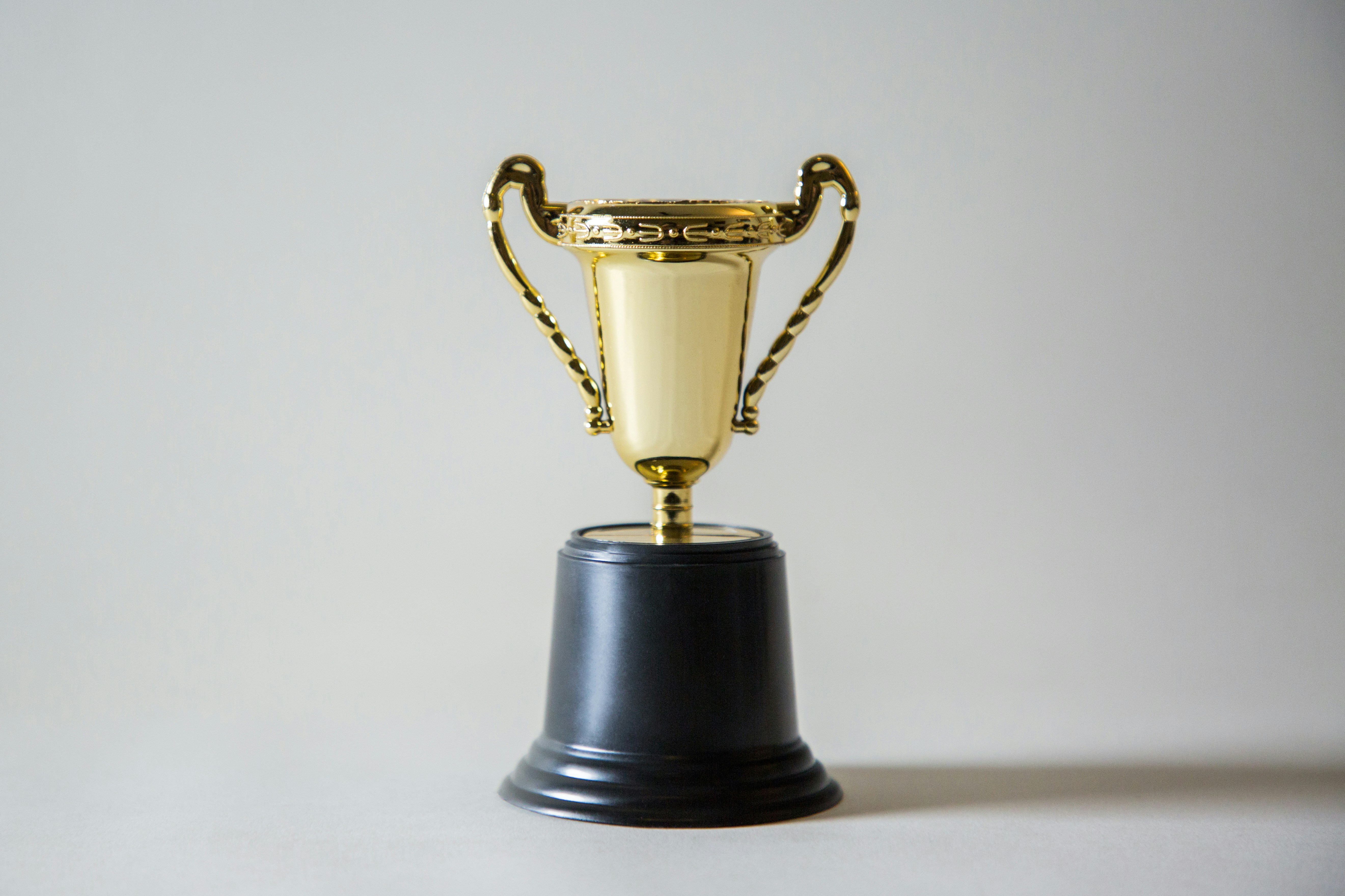 Image of a gold trophy on a neutral background. Photo by Giorgio Trovato on Unsplash Free License