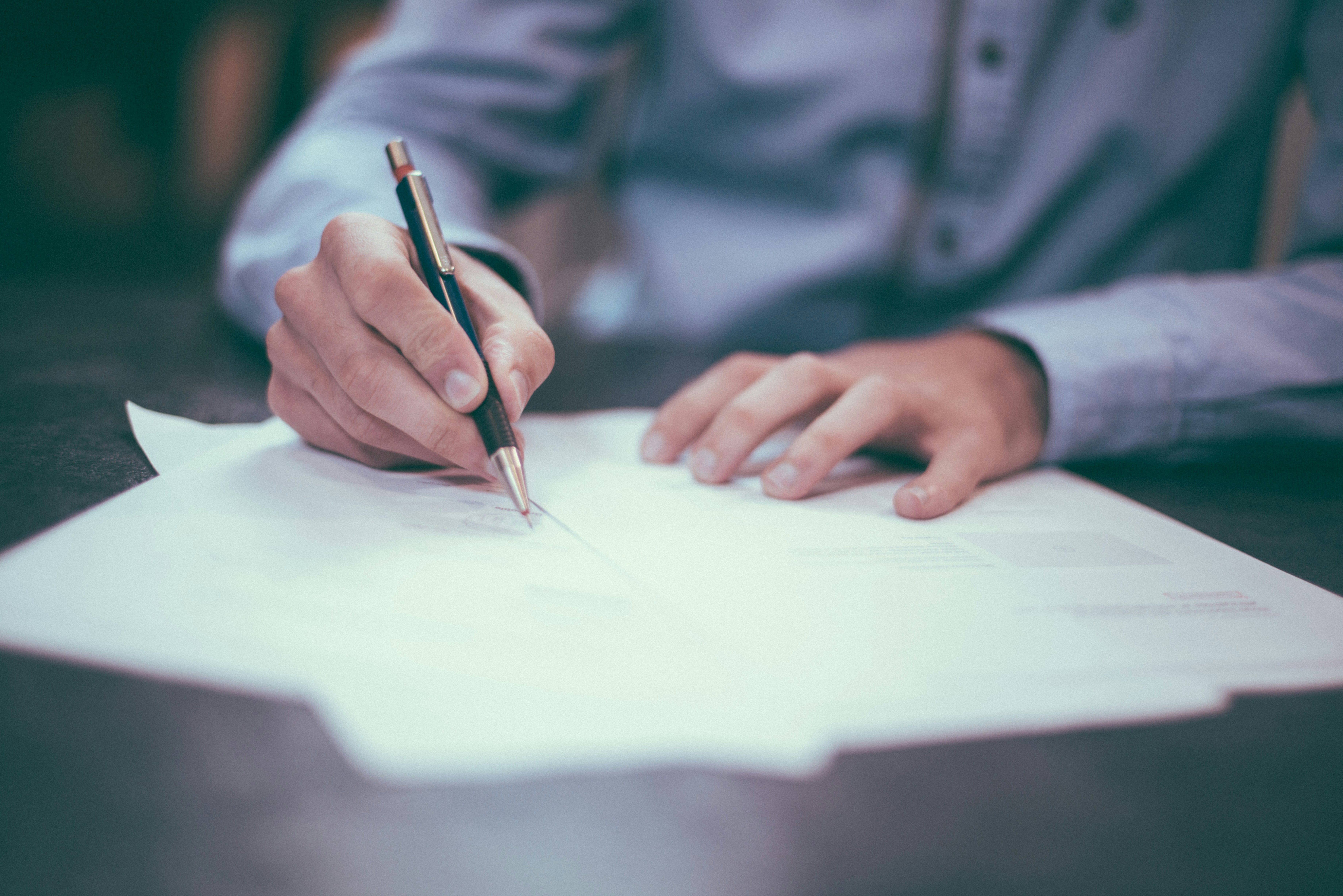 Image of a person filling out an application with paper and pen. Photo by Scott Graham on Unsplash free license.