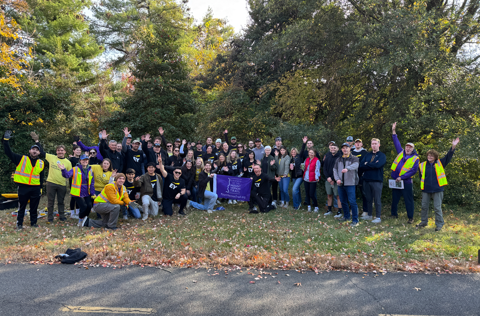 Large group of volunteers celebrating under the shade of fall trees