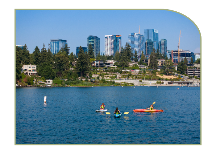 Three people kayak on Lake Washington on a sunny day. The city of Bellevue is in the background