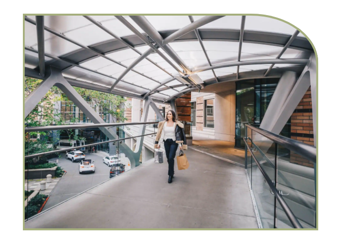 A woman walks on an elevated covered walkway that spans over the street to connect her hotel to nearby shops