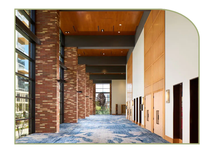 Tall hotel corridor with brick walls and floor to ceiling windows 
