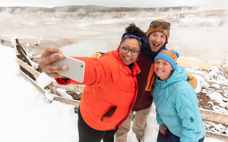 group of three friends taking a selfie at an overlook