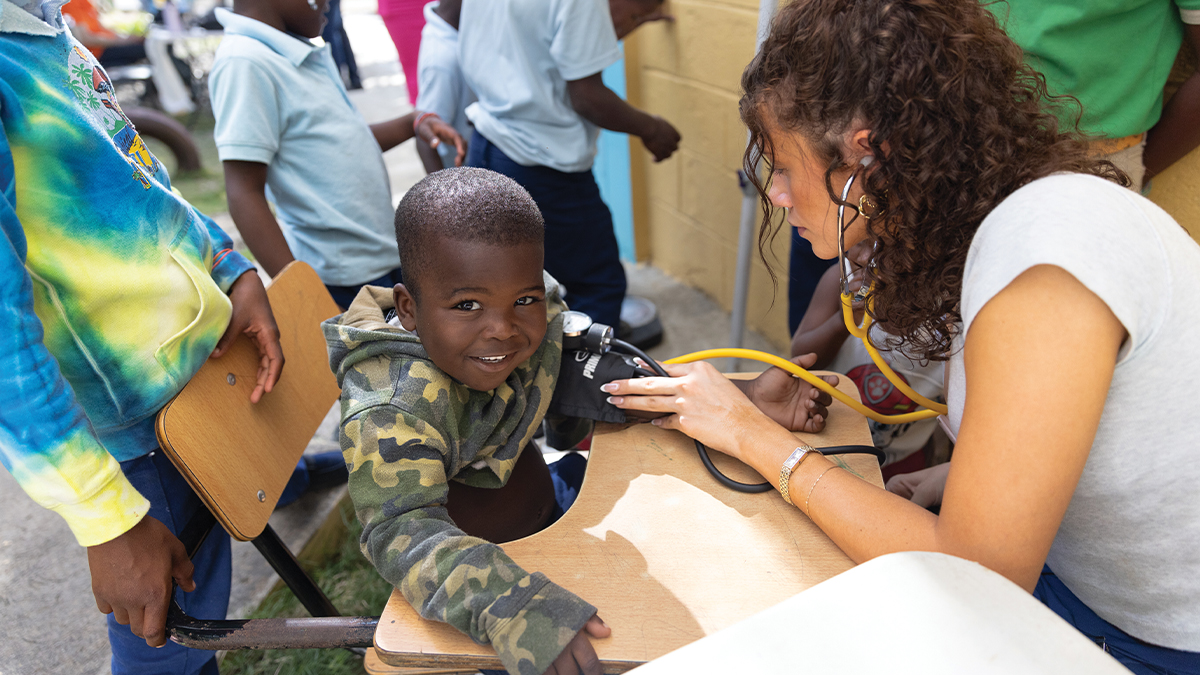 Gisele Oakes, a general volunteer, takesvitals of a pediatric patient in the DR ASC.