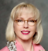 A person wearing glasses and a pink jacket

Description automatically generated