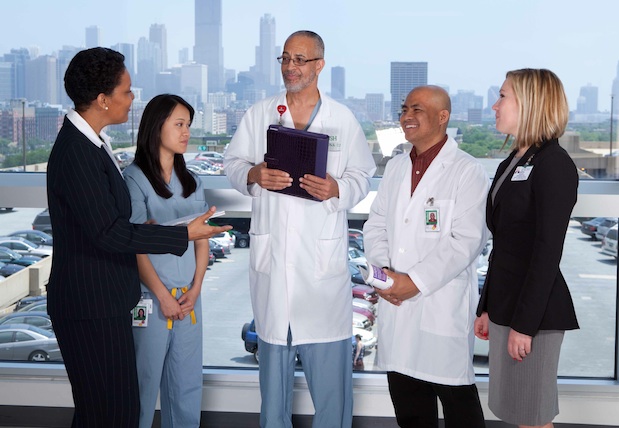 A health administration professor talks with students and colleagues