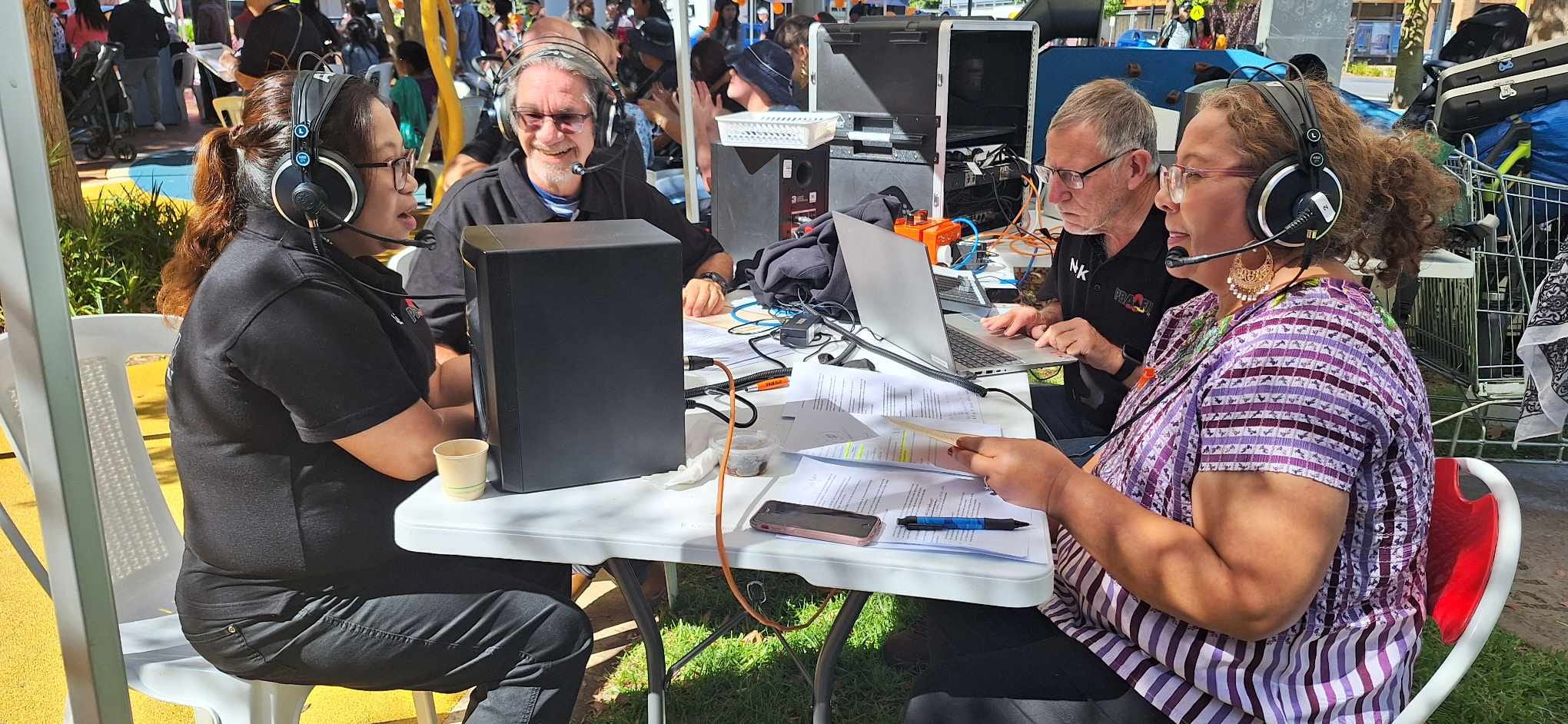 Four presenters from PBA-FM sitting around a table at an Outside Broadcast