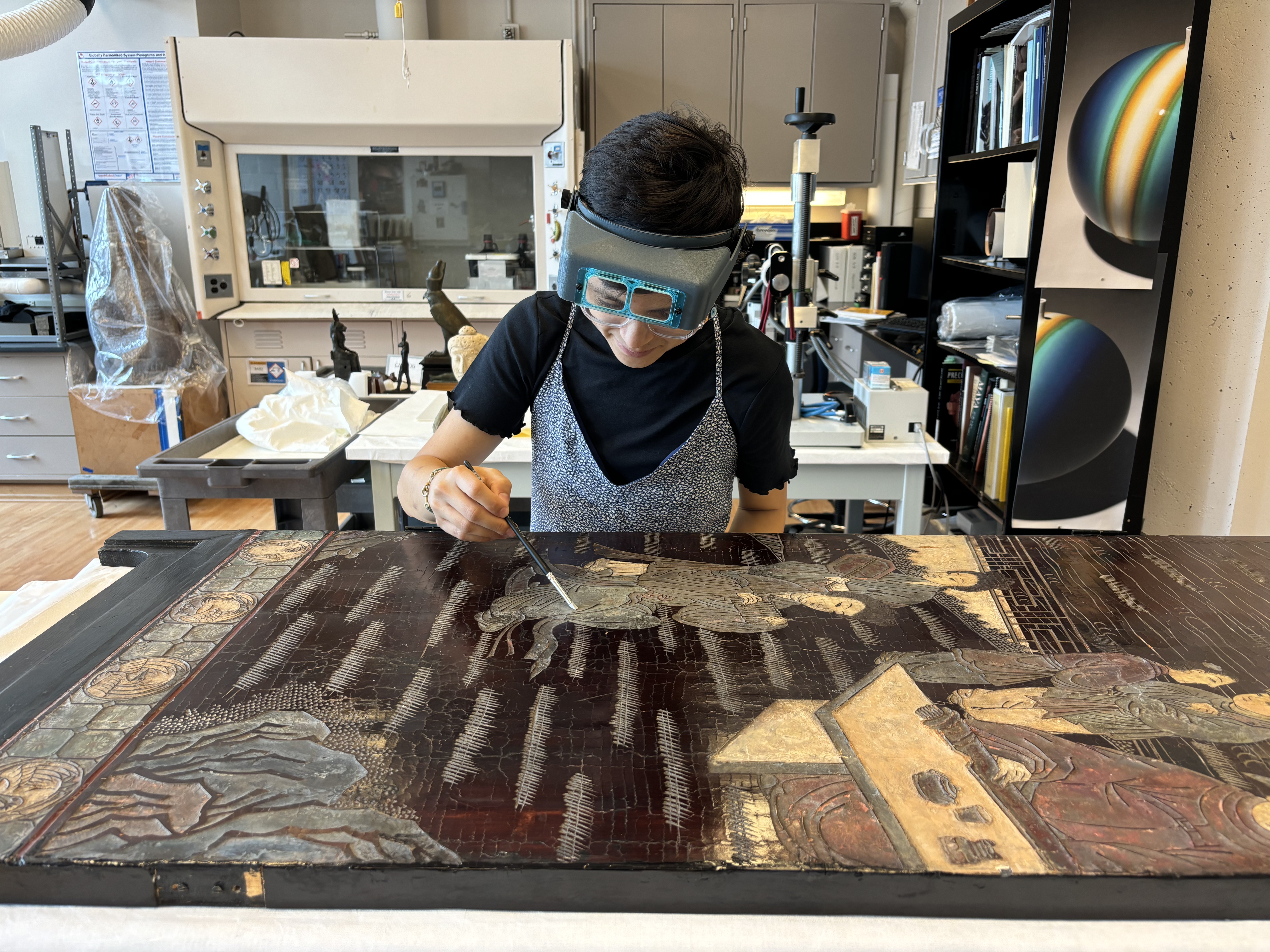 A conservator inspects a large object in a laboratory setting