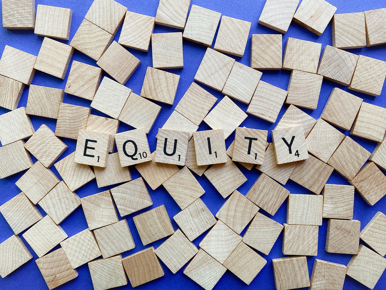 wooden tiles on a blue background have letters that spell out the word equity