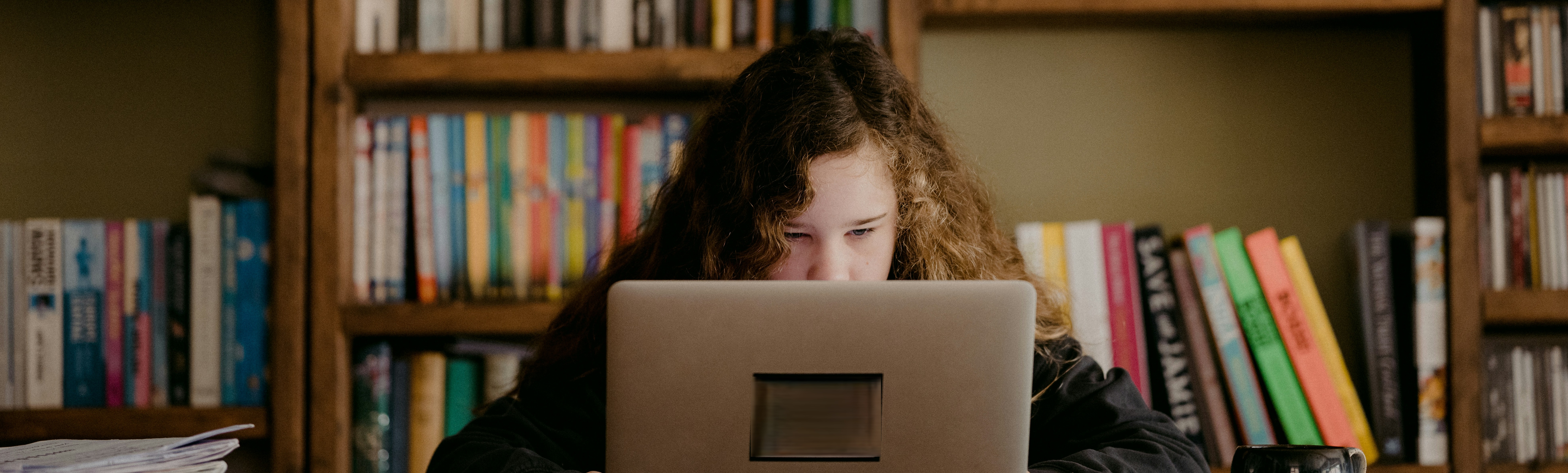 Girl at laptop with shelves of books behind her