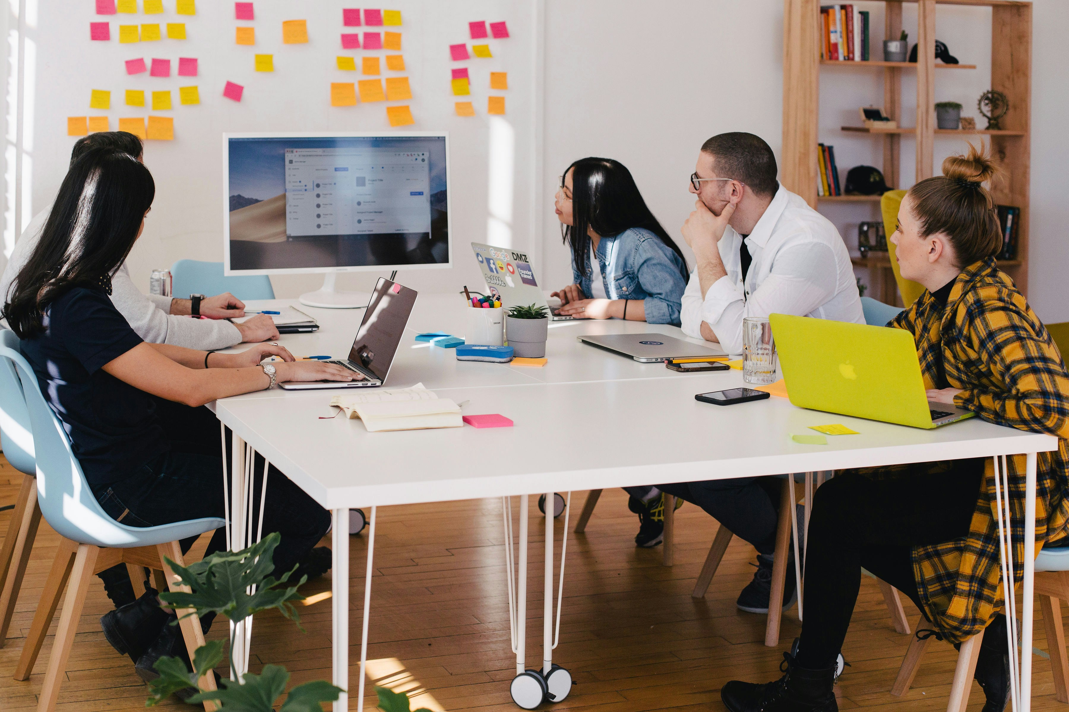 People around a table with colorful sticky notes on the wall