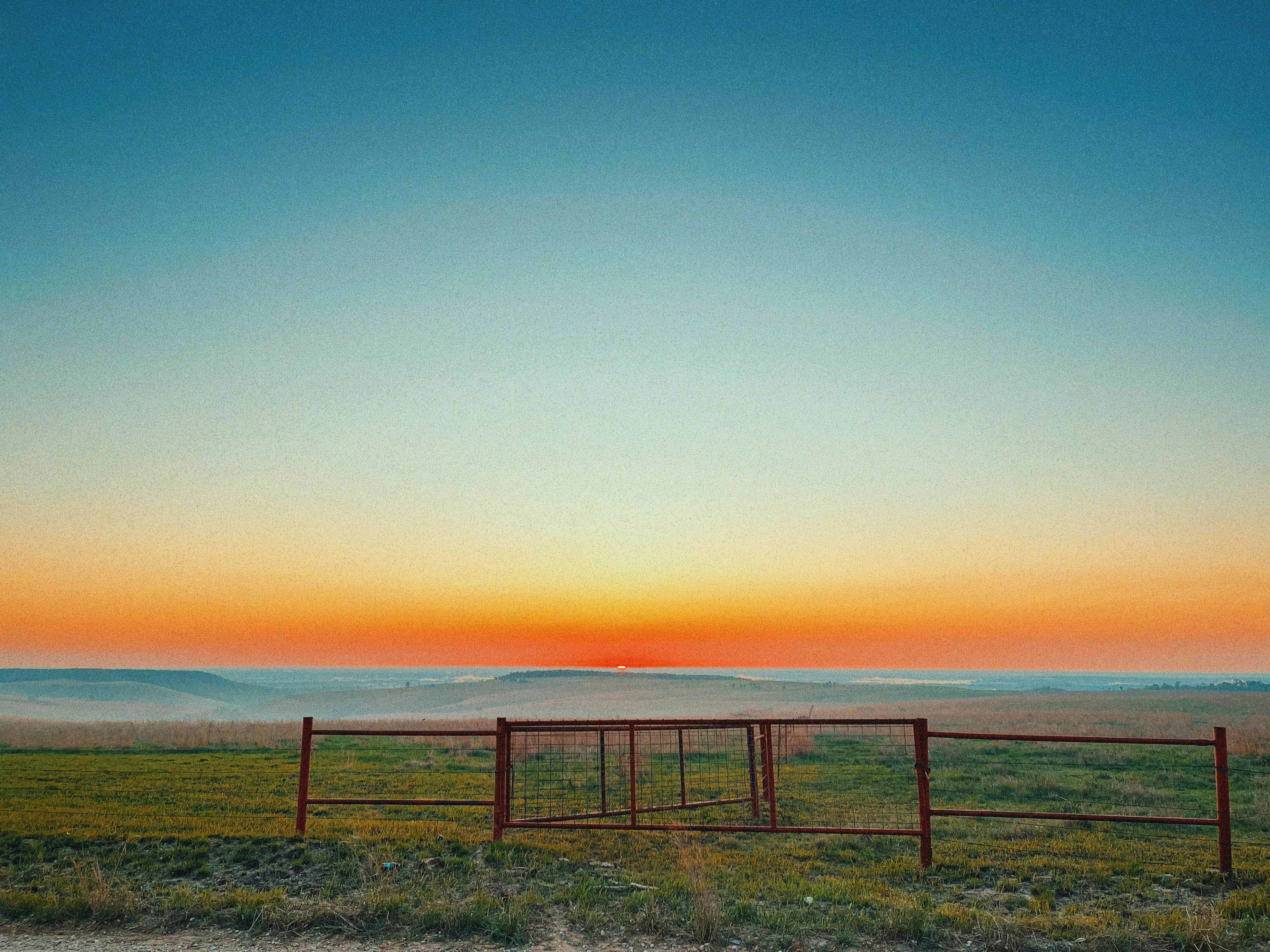 Prairie with a gate and sunset