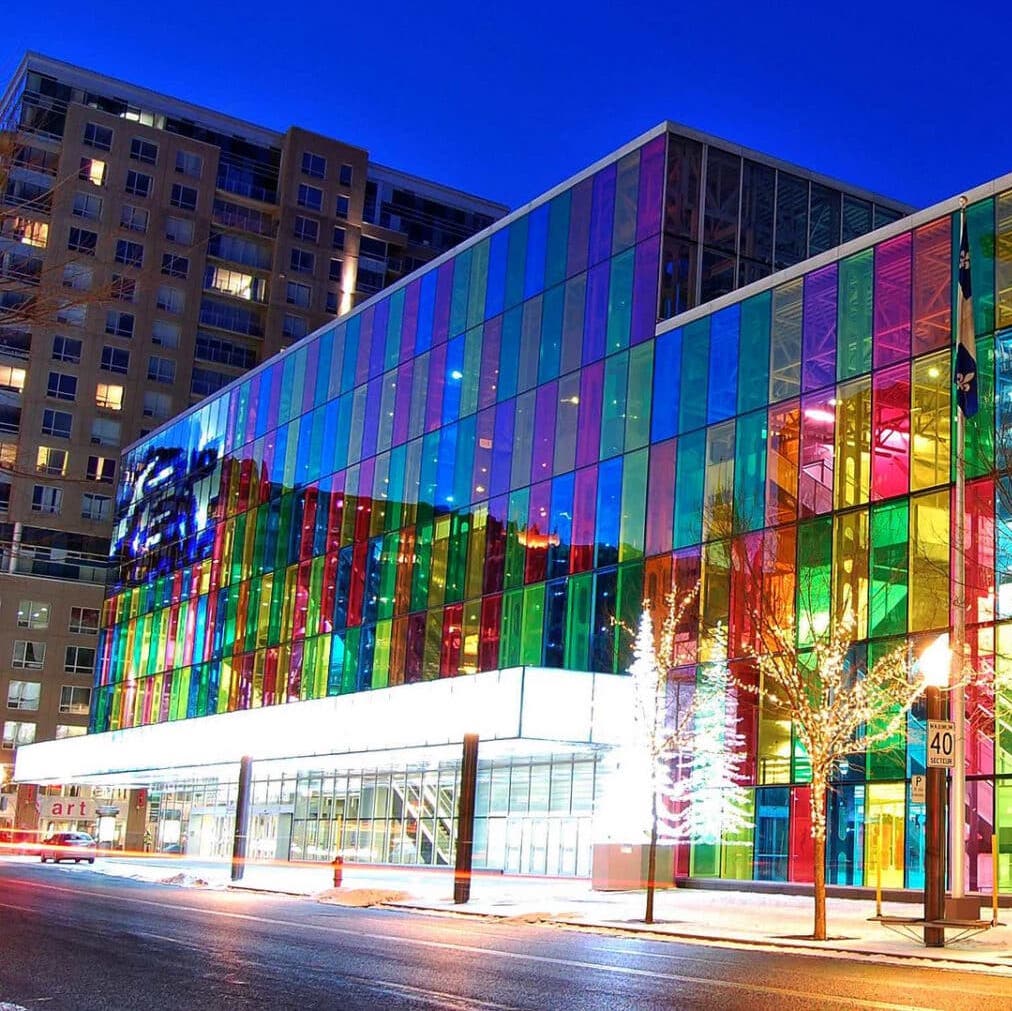Palais des congrès de Montréal is shown with its main wall of angular windows tinted with many colors similar to stained glass