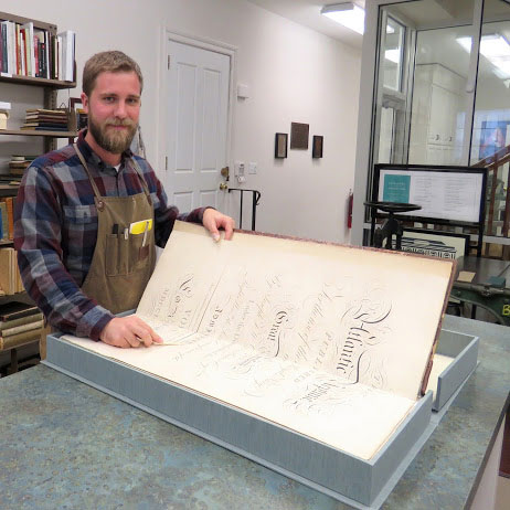 James Davis holds an oversized book open on a table