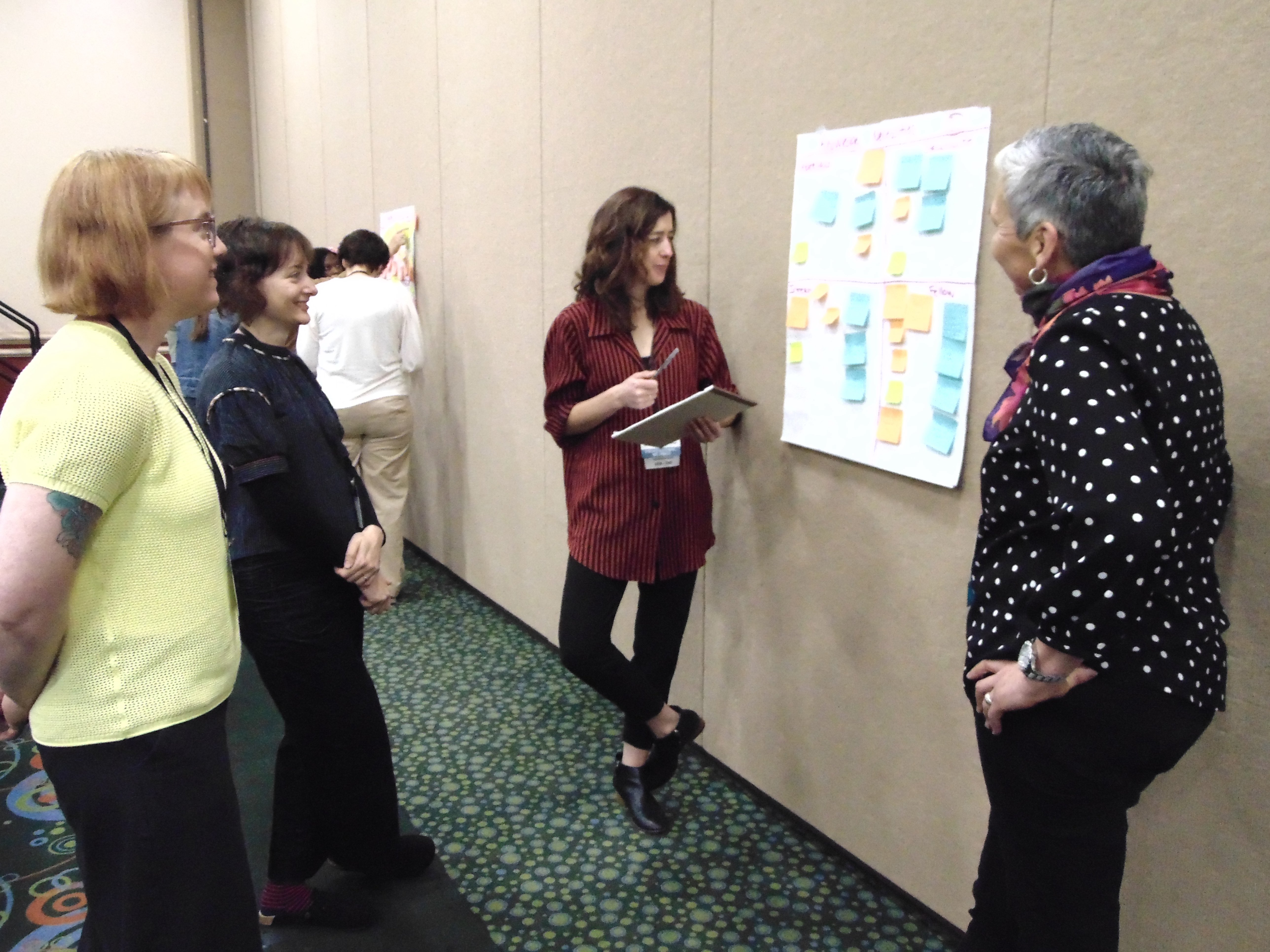 A small group of participants stand by a large paper with sticky notes attached