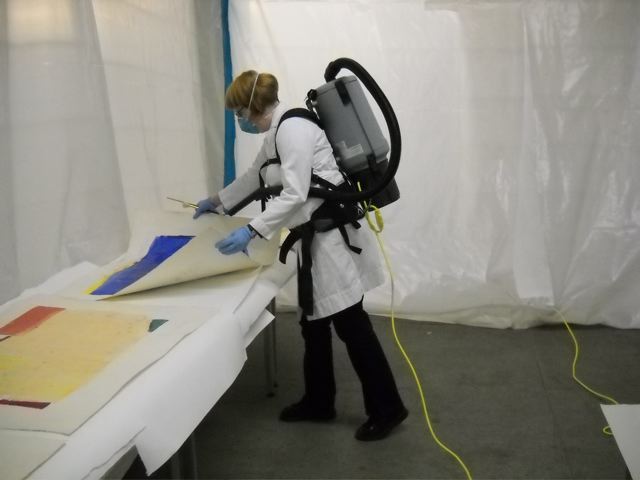Woman wearing PPE and moving artwork.