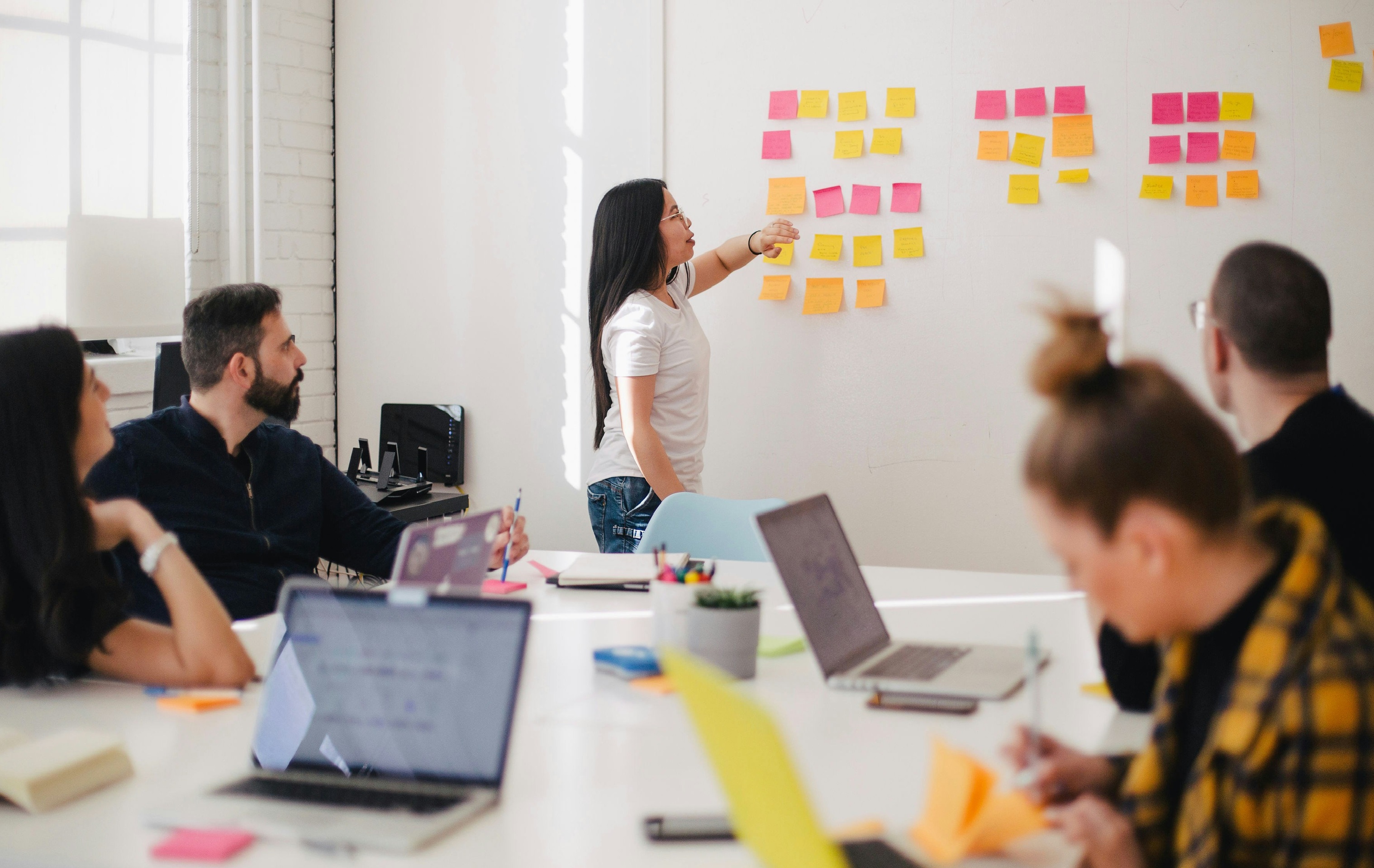 Image of group of people at a table listening to a woman talking.
