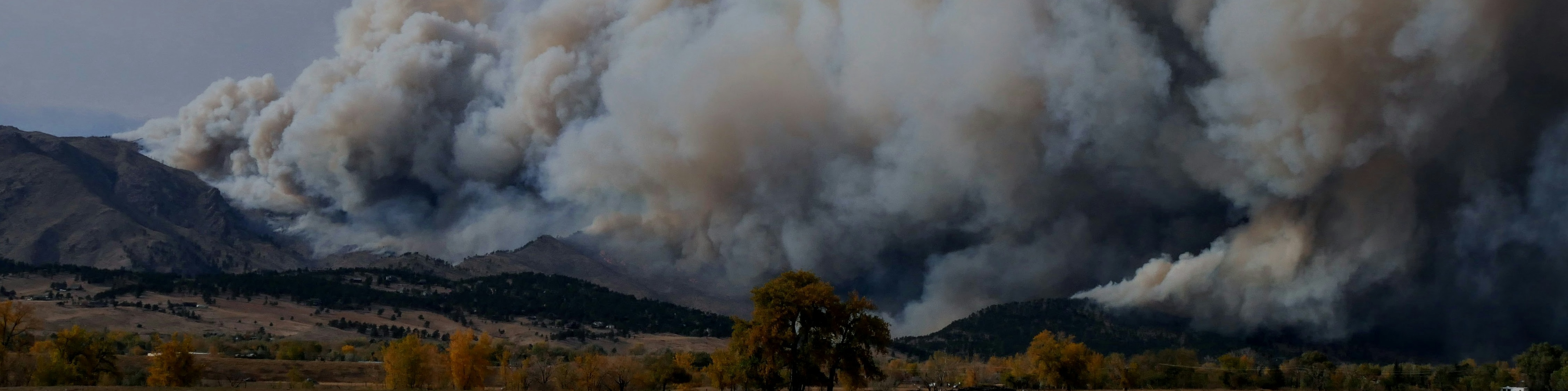 Image of large smoke plume over a mountain.