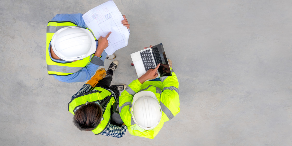 Three workers in vests compare safety notes