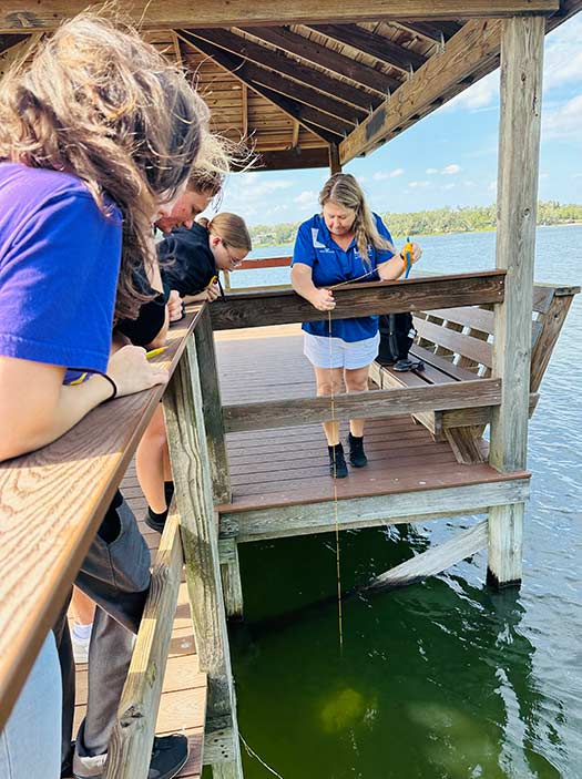 Students watch instructor perform water quality test