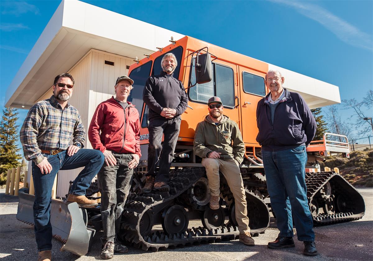 group of men standing in front of snowcat vehicle