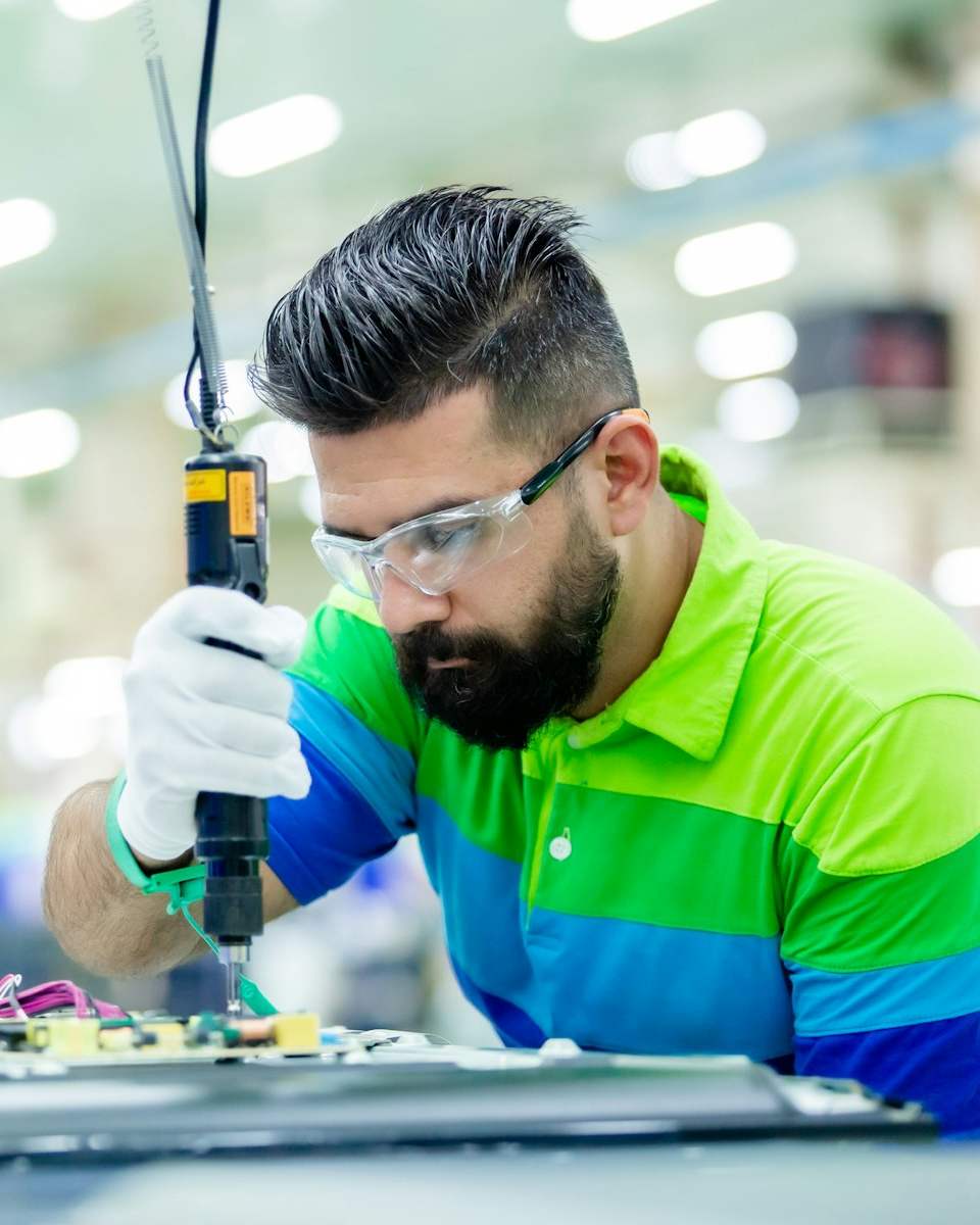 A technician in safety glasses assembling an electronics board