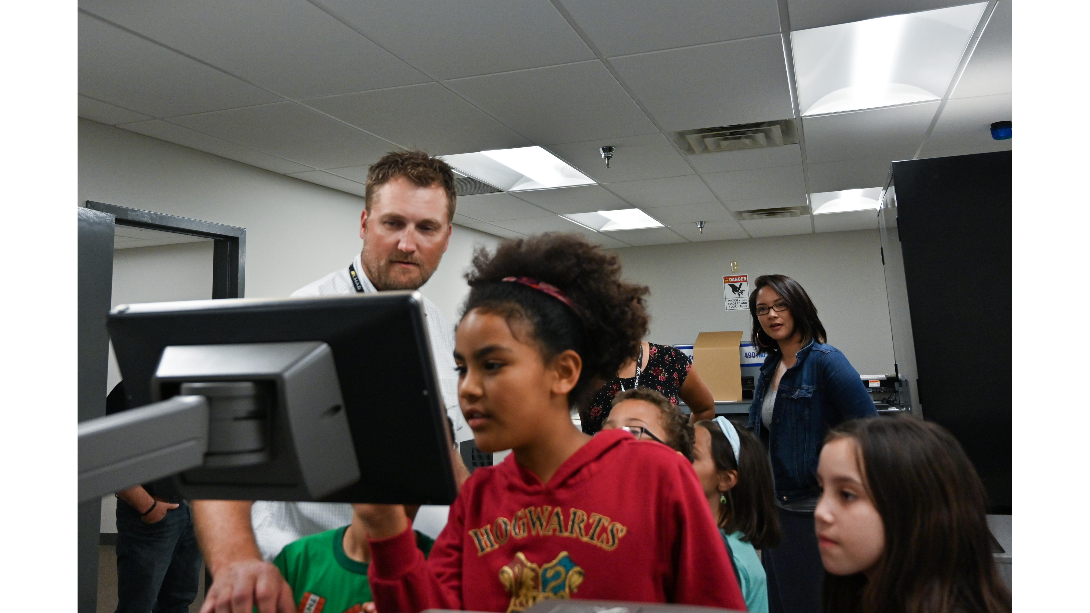 Children gathered, looking at lab computer screen together.