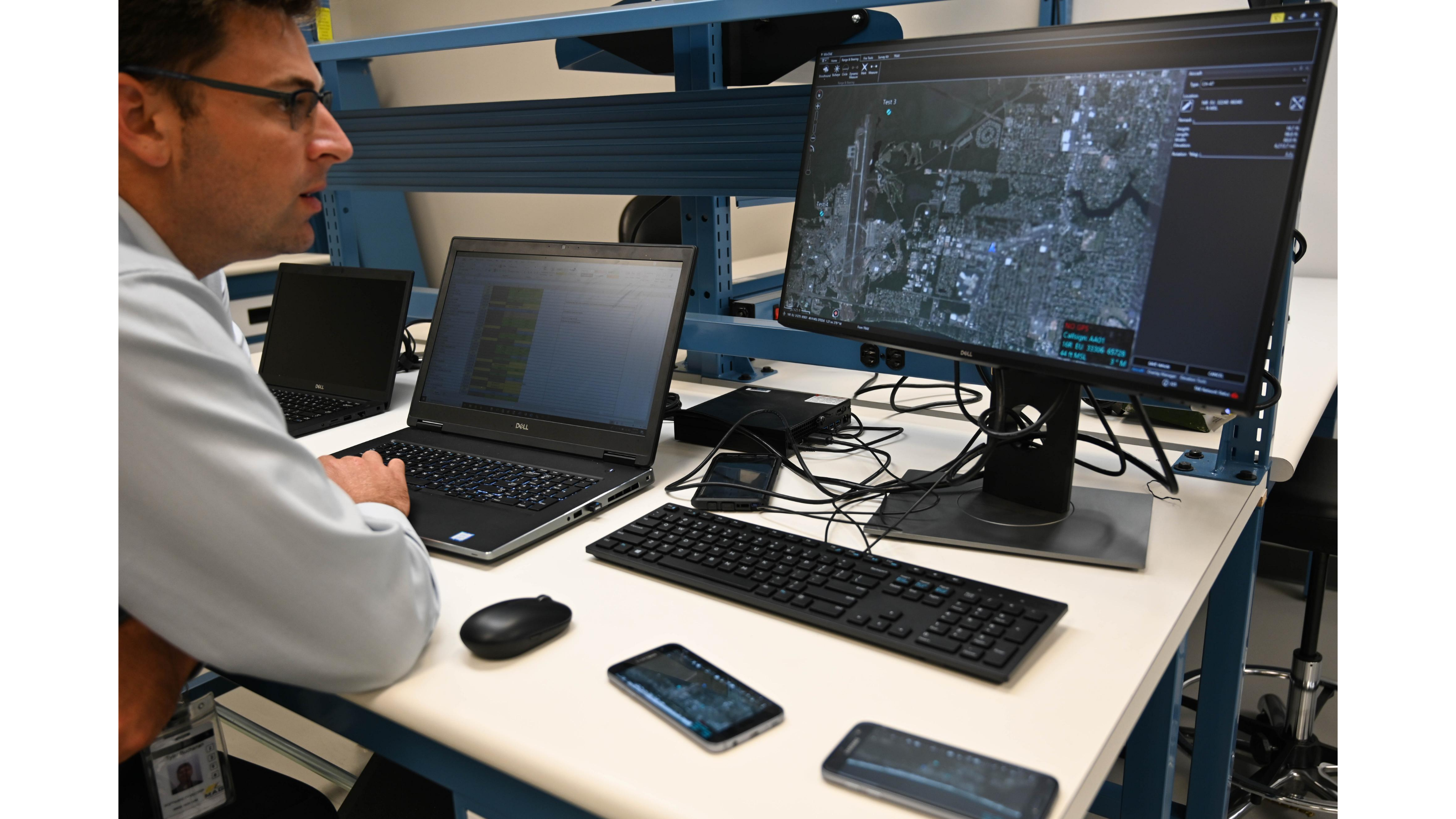 Man working at computer, looking at satellite imaging. 