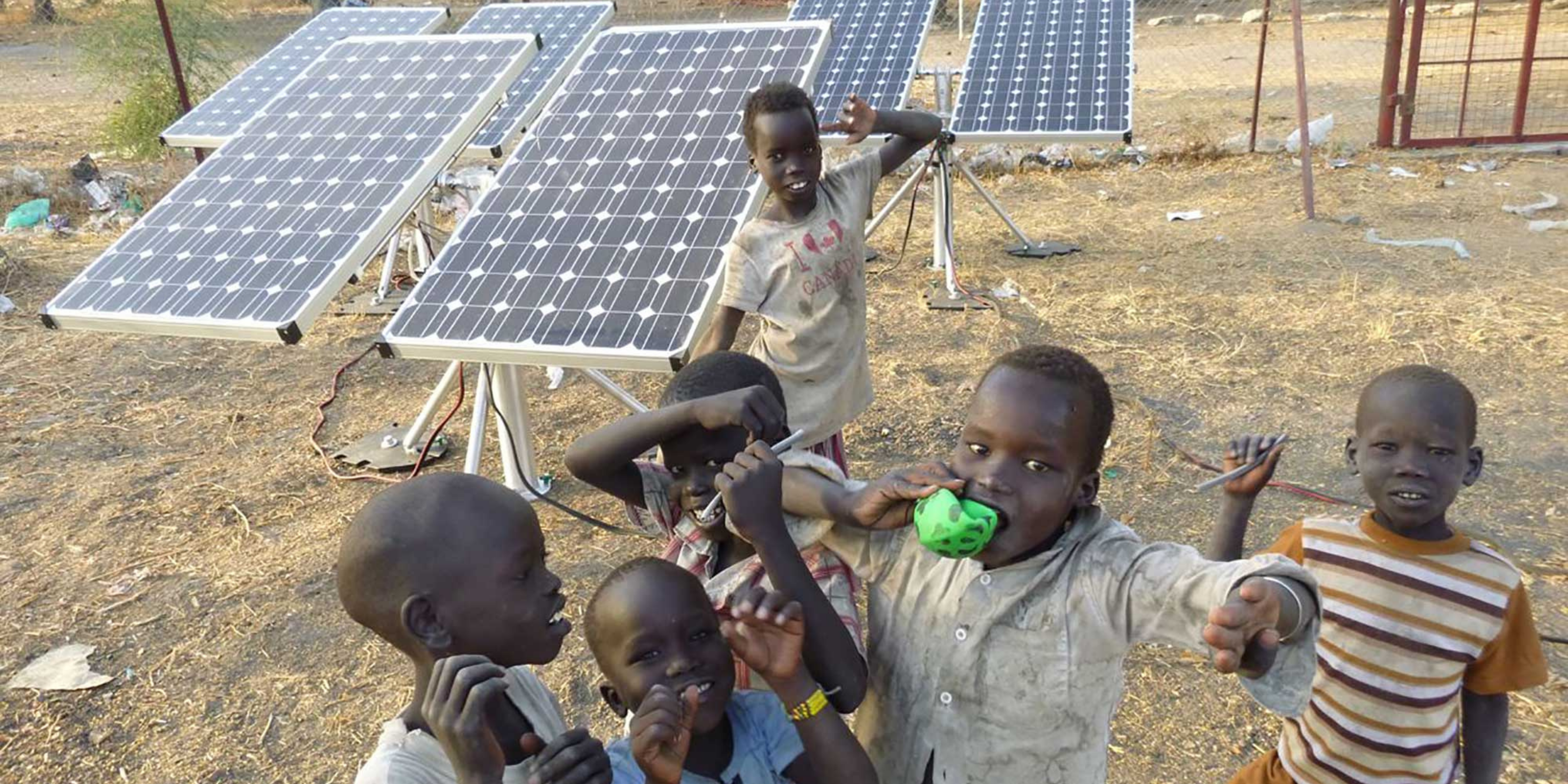 Group of children posing for photo with solar panels.