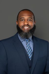 Black man, dark hair and facial hair, smiling