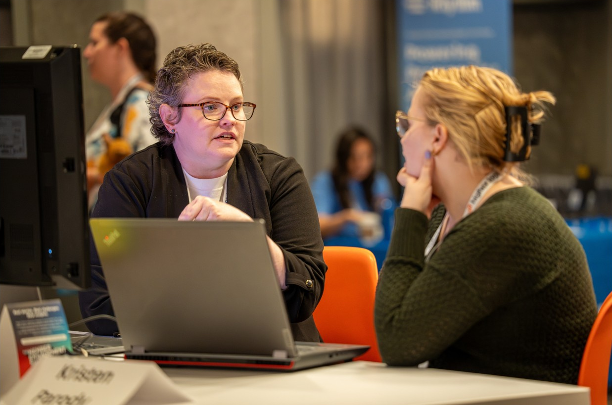 Two people sharing ideas across a conference table.