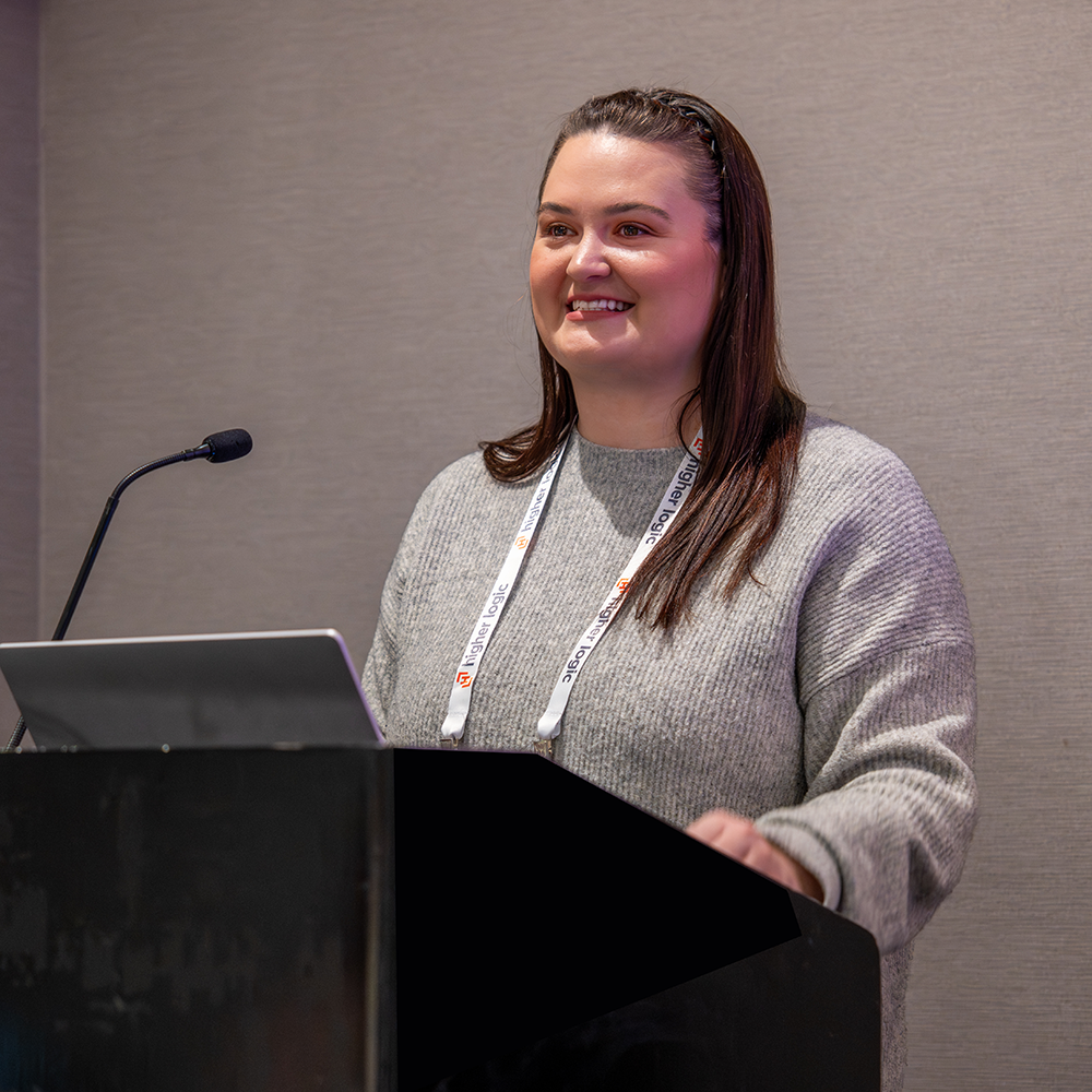 A presenter sharing her experience at a conference podium.