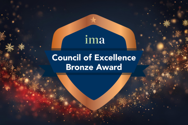 A bronze shields shaped badge against a dark background with a sweep of bronze glitter